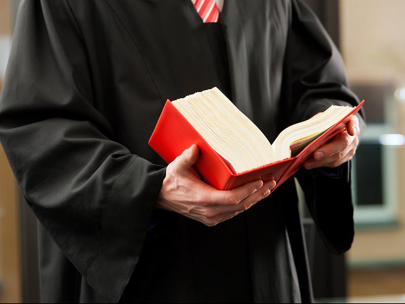 Personne en robe noire tenant un code rouge