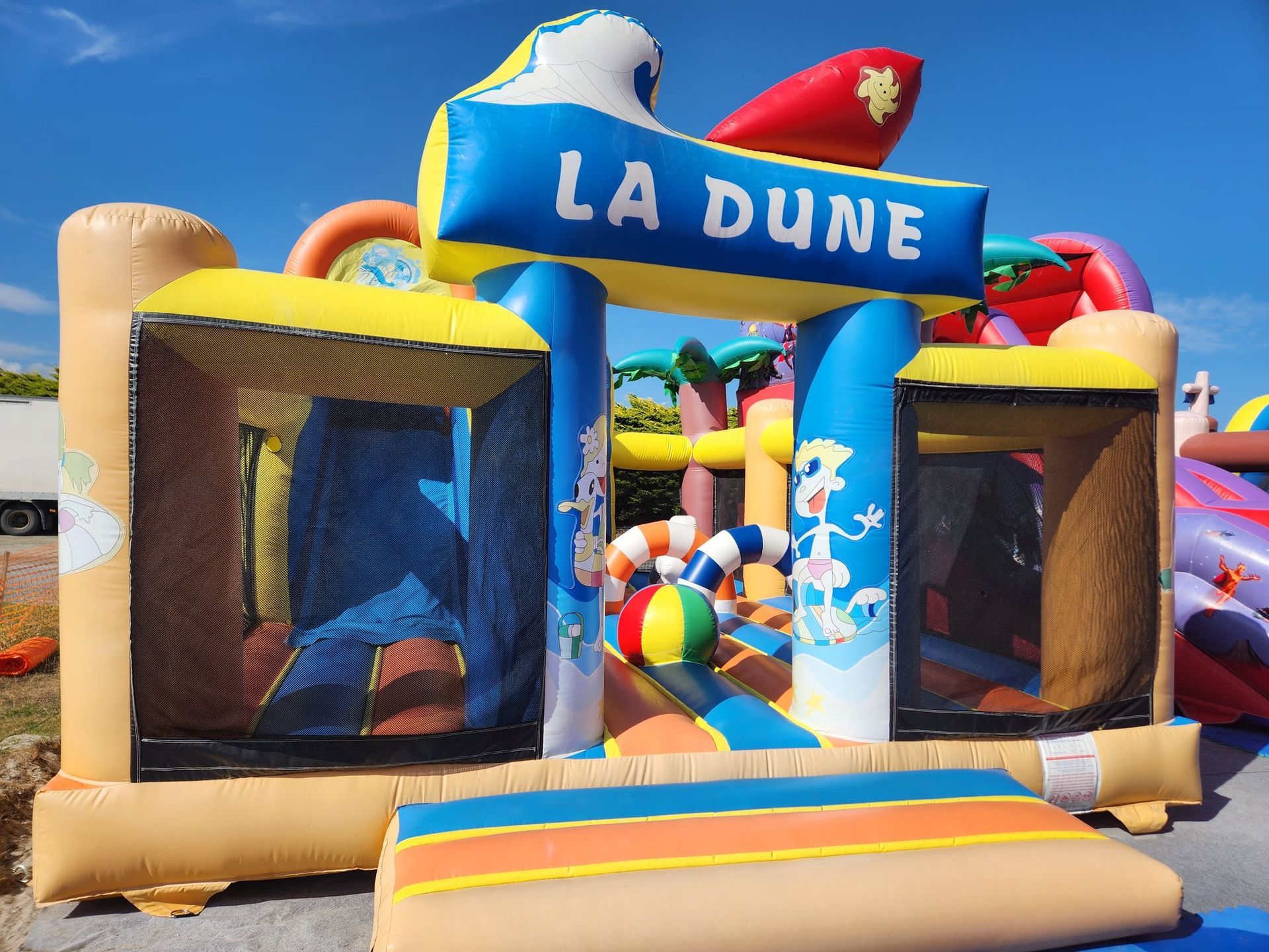 Maison gonflable La Dune sur le thème de la plage, fond ciel bleu.