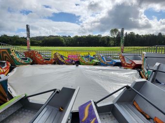 Manège de fête foraine avec des bateaux colorés sur une plate-forme circulaire, ciel nuageux en arrière-plan.