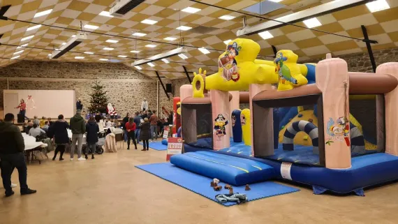 Événement intérieur avec château gonflable, personnes et tables.