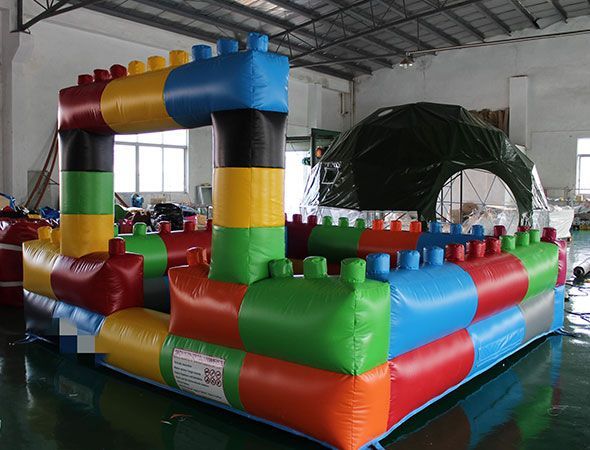 Structure de jeu gonflable colorée ressemblant à des blocs de construction ; décor intérieur.