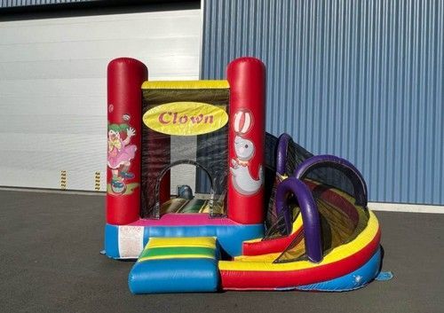 Maison gonflable sur le thème du clown avec toboggan. Couleurs : rouge, jaune, bleu et vert.