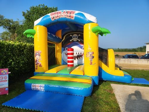 Maison gonflable sur le thème des pirates ; jaune, bleu et vert ; à l'extérieur sur l'herbe.