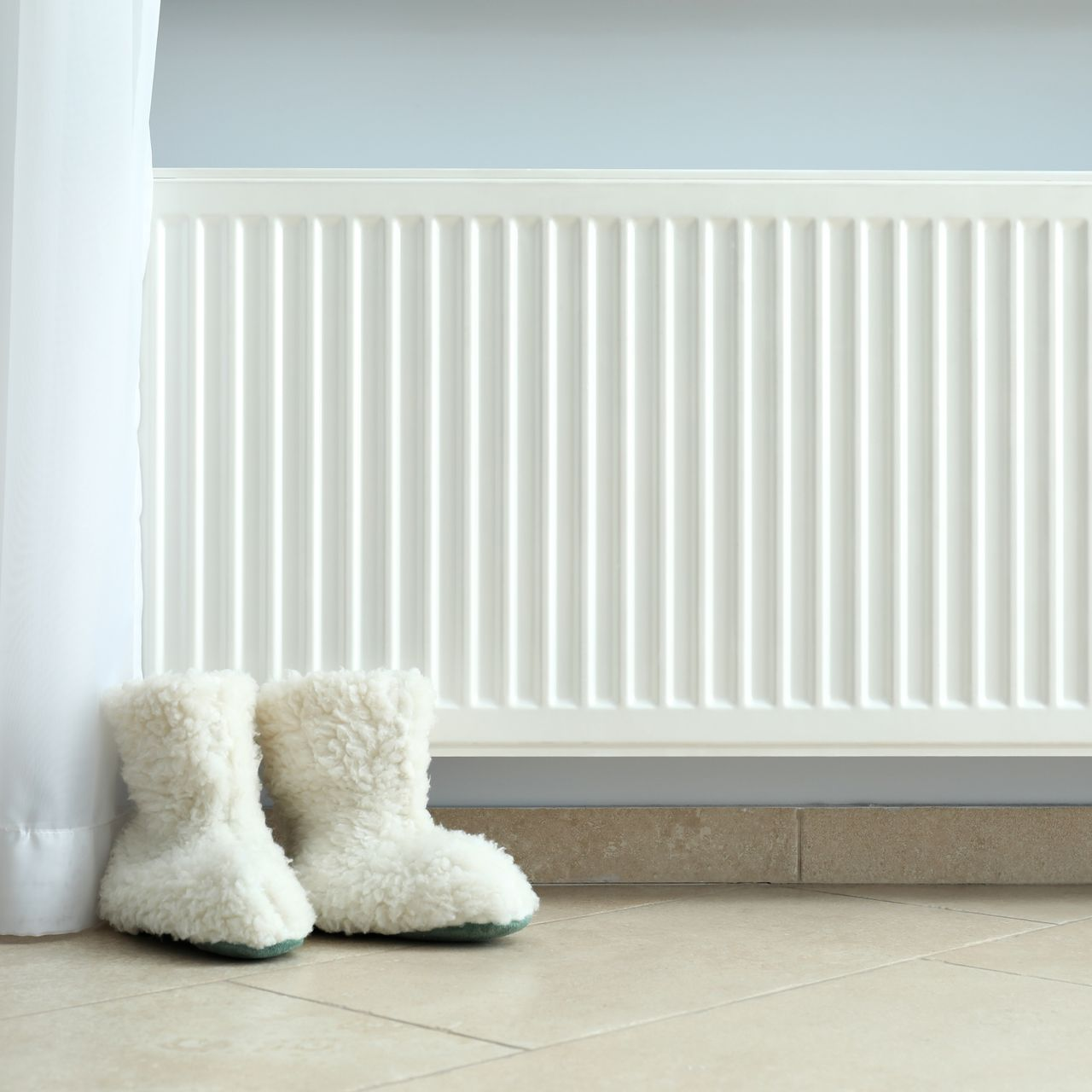 Un radiateur blanc, près d'un voile blanc.