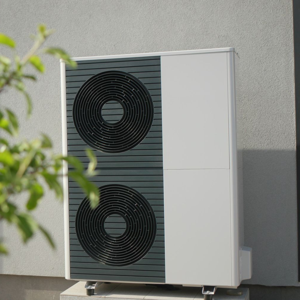 Unité de climatisation extérieure avec deux ventilateurs noirs sur une plateforme murale