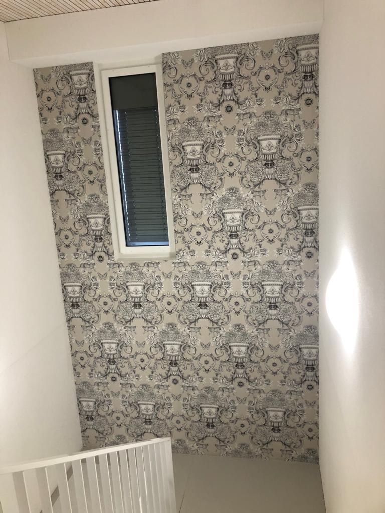 Tapezierte Wand mit Fenster; beiges und dunkelblaues Muster mit weißem Geländer.