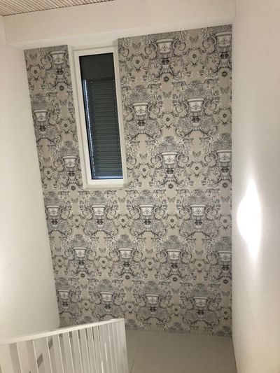 Tapezierte Wand mit Fenster; beiges und dunkelblaues Muster mit weißem Geländer.