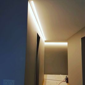 Flur mit eingelassener LED-Lichtleiste an der Decke. Licht erhellt Wände und Boden.