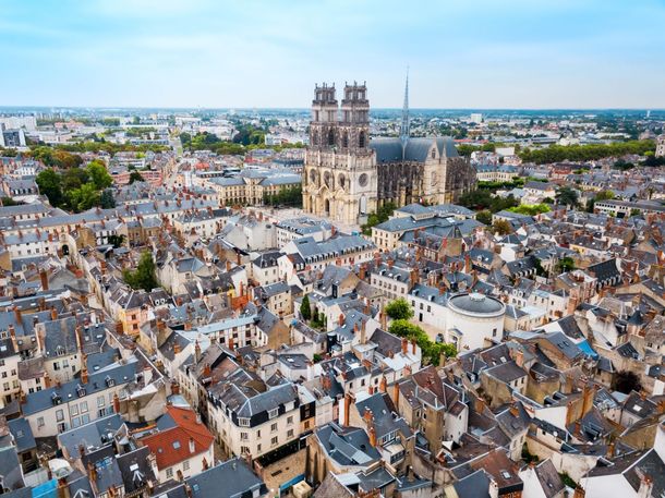 Vue aérienne de la cathédrale d'Orléans dominant les rues et les toits denses et historiques de cette ville française.