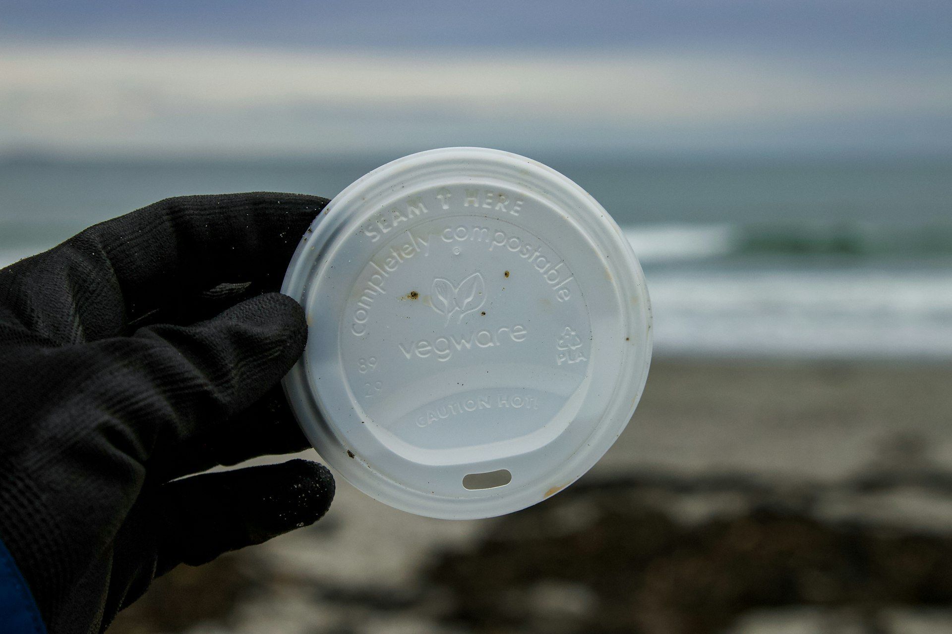 Couvercle de gobelet « compostable » ramassé sur une plage, symbole des allégations visées par EMPCO