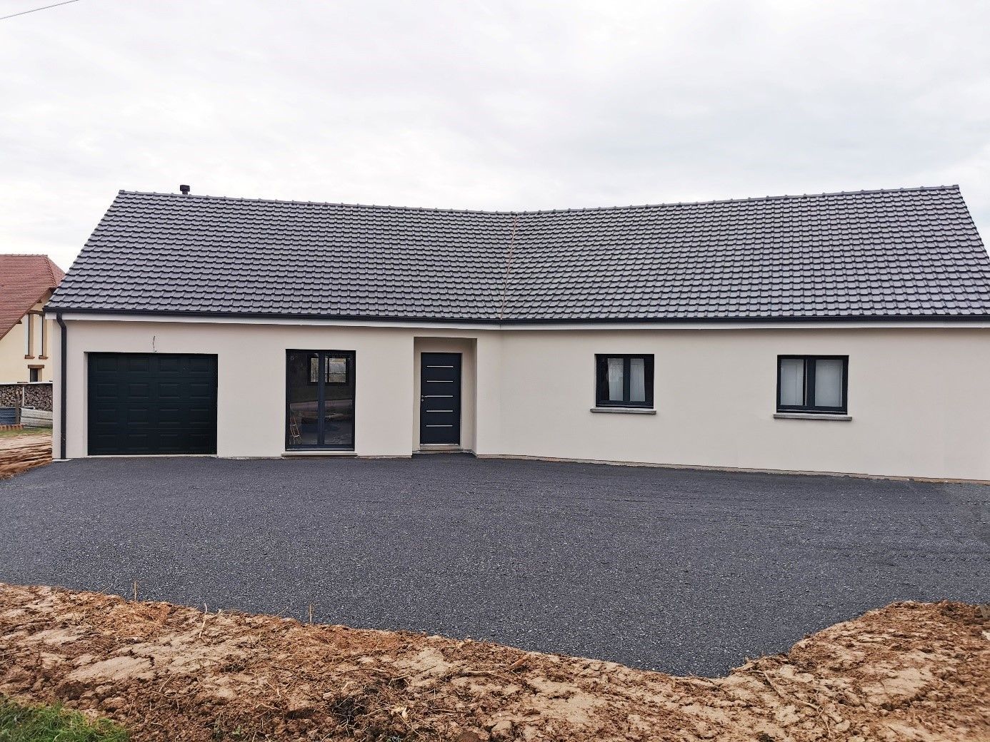 Maison avec menuiseries noires et cour gravillonnée