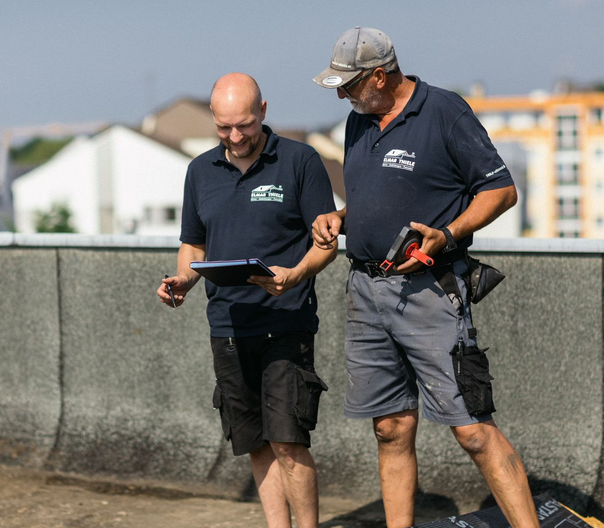 Dachdecker sitzt auf einem Dach und deckt es mit neuen Dachziegeln