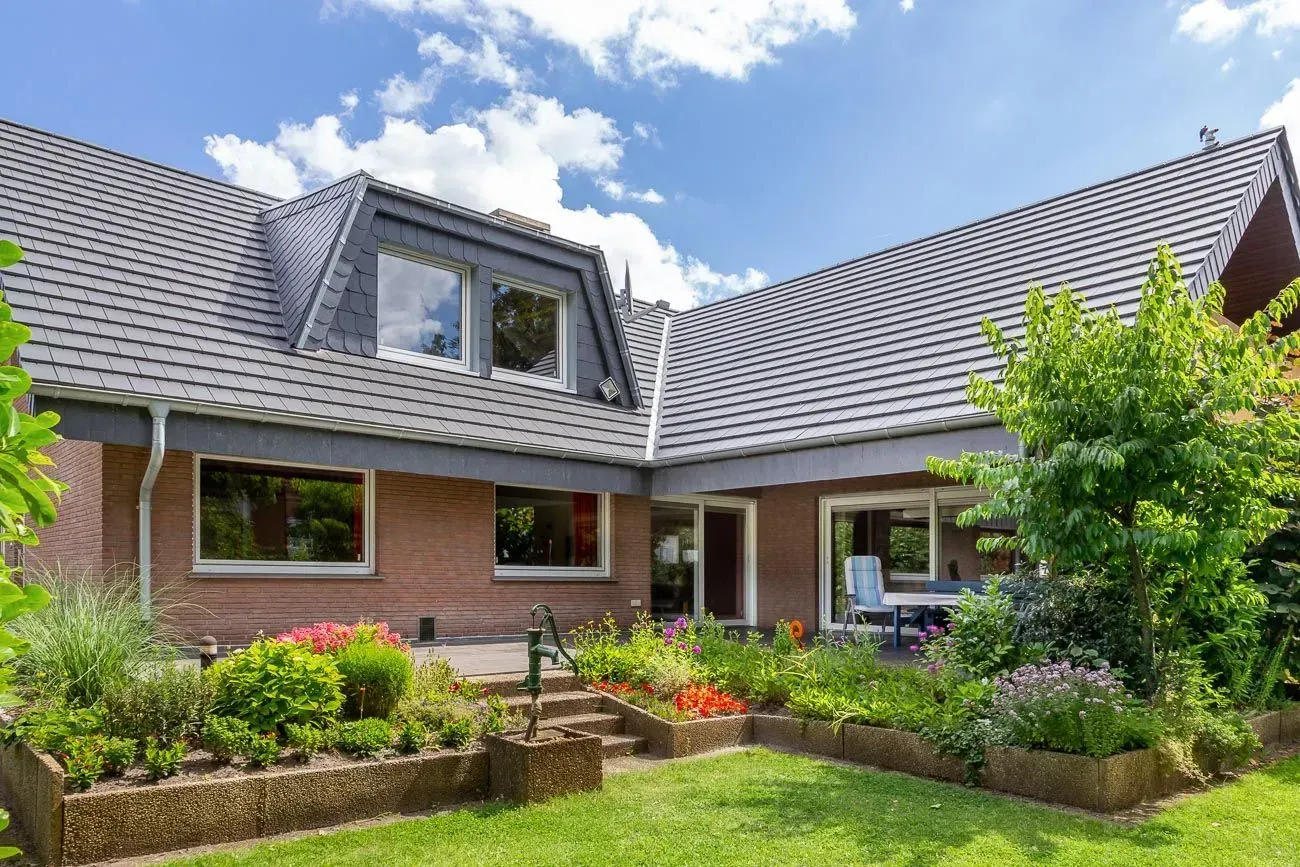 Haus mit ordentlich gedecktem Dach und blühendem Garten