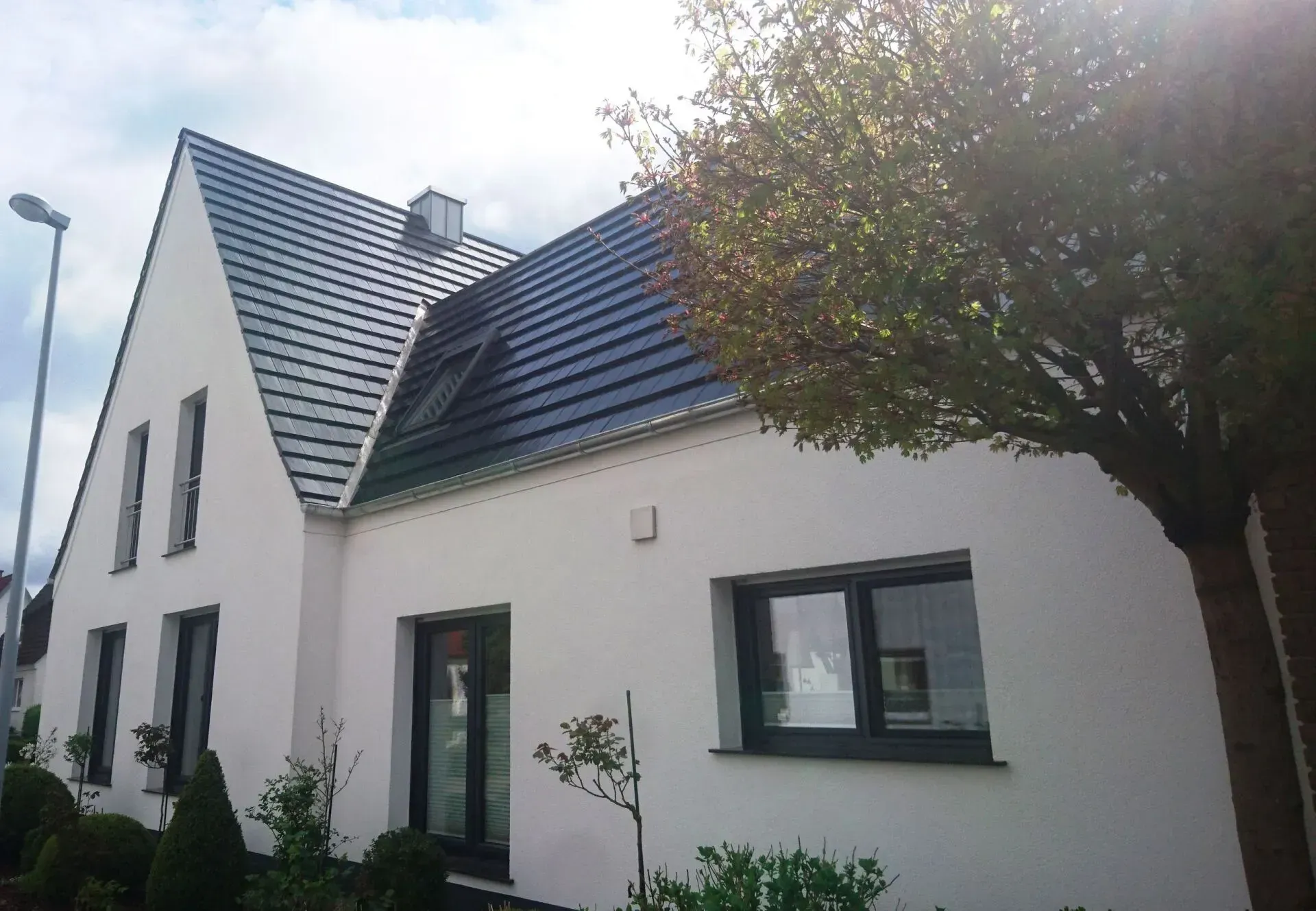 Modernes weißes Haus mit dunkel gedecktem Dach