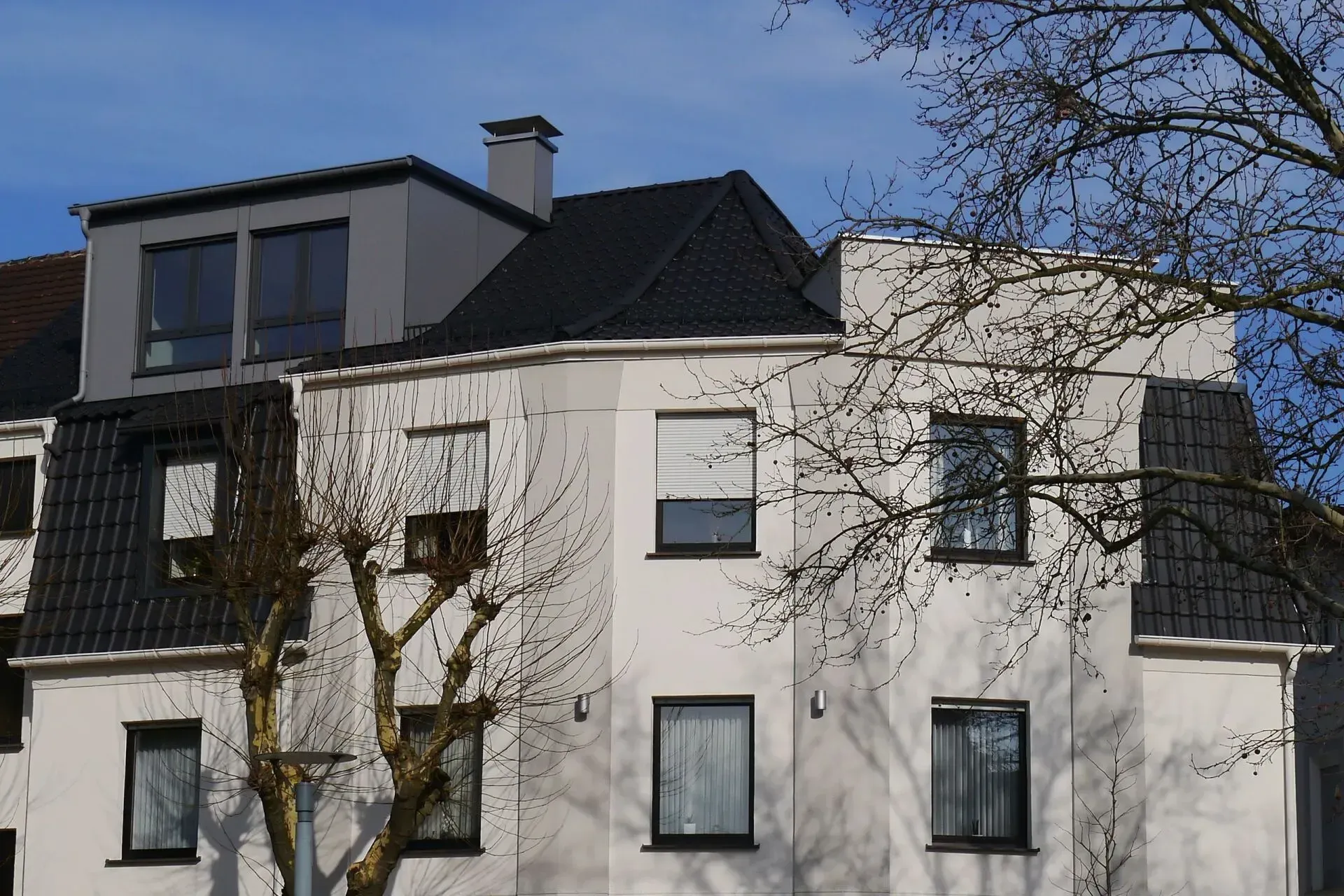 Modernes weißes Eckhaus mit dunkel gedecktem Dach