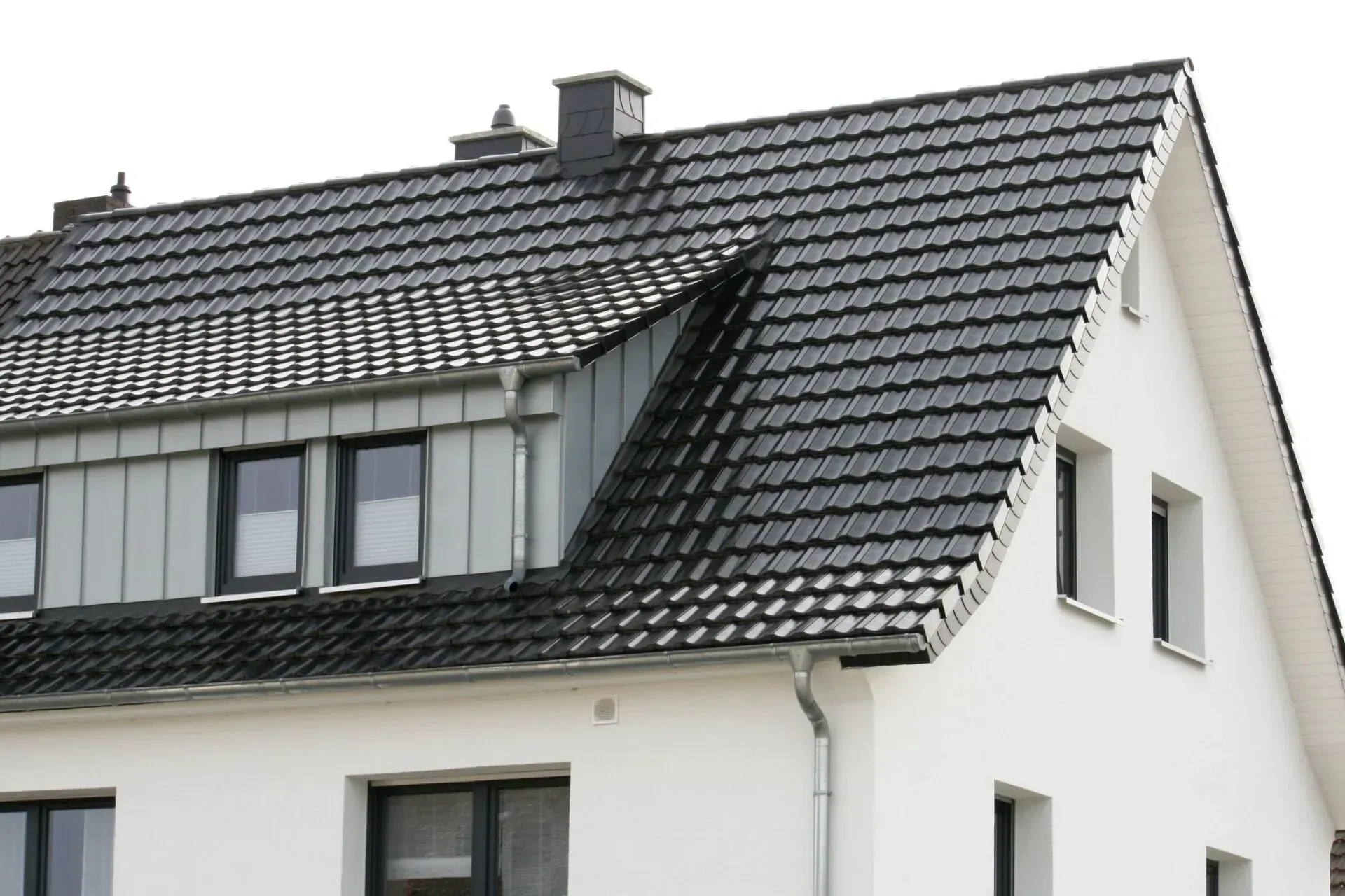 Modernes weißes Haus mit dunkel gedecktem Dach