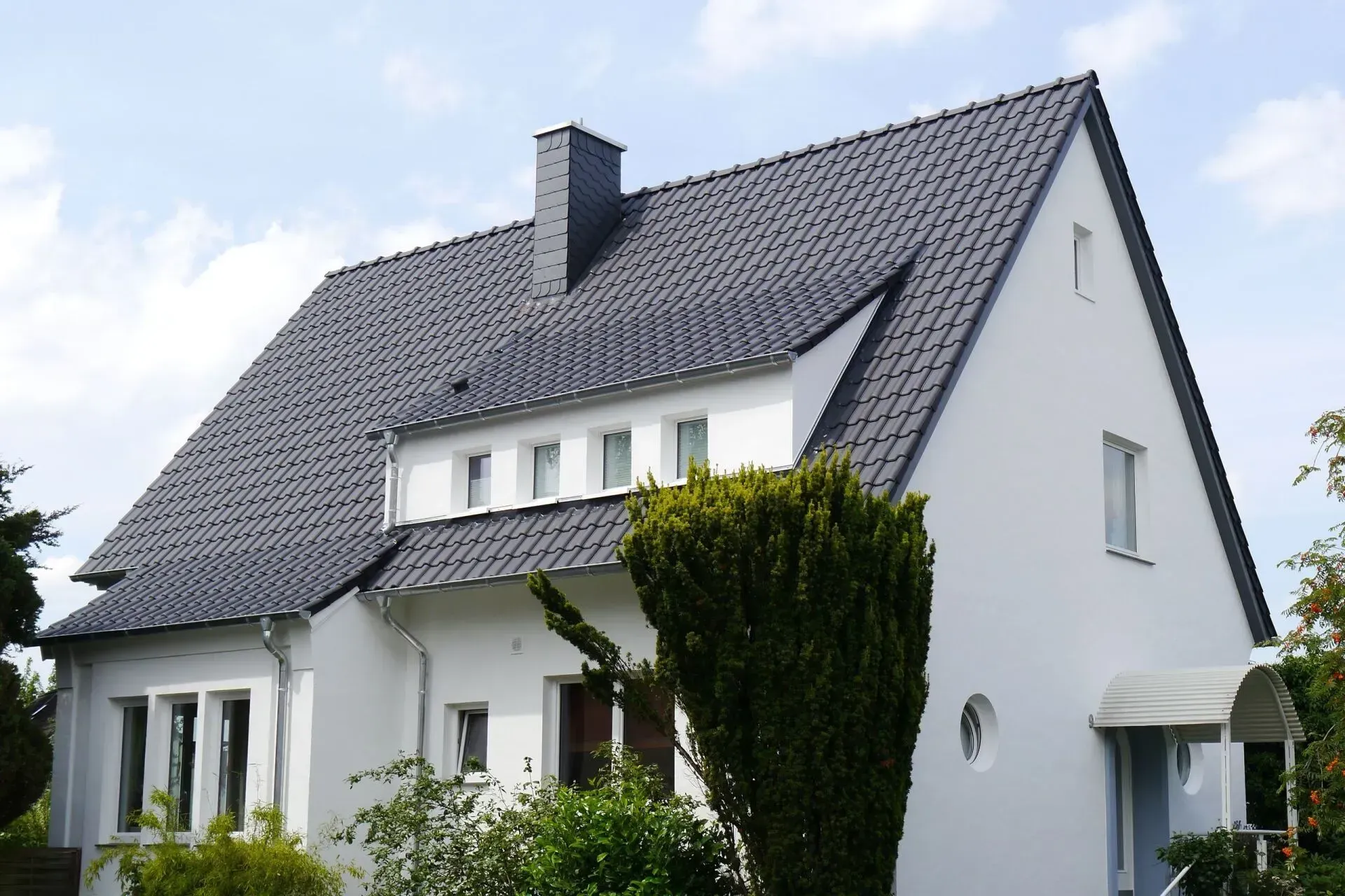 Modernes weißes Haus mit dunkel gedecktem Dach
