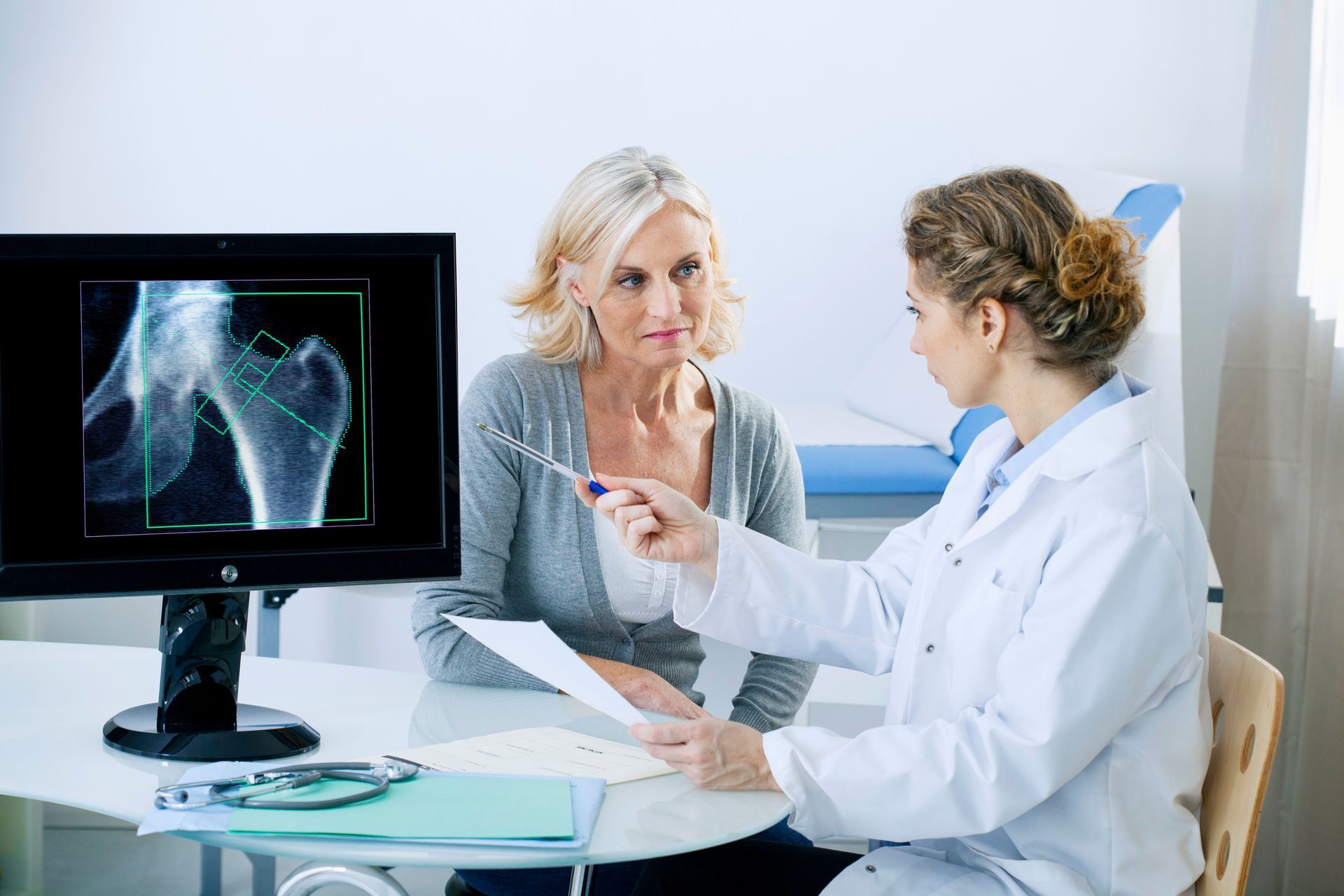 Une femme médecin qui explique les résultats d'analyse de densité osseuse à une patiente