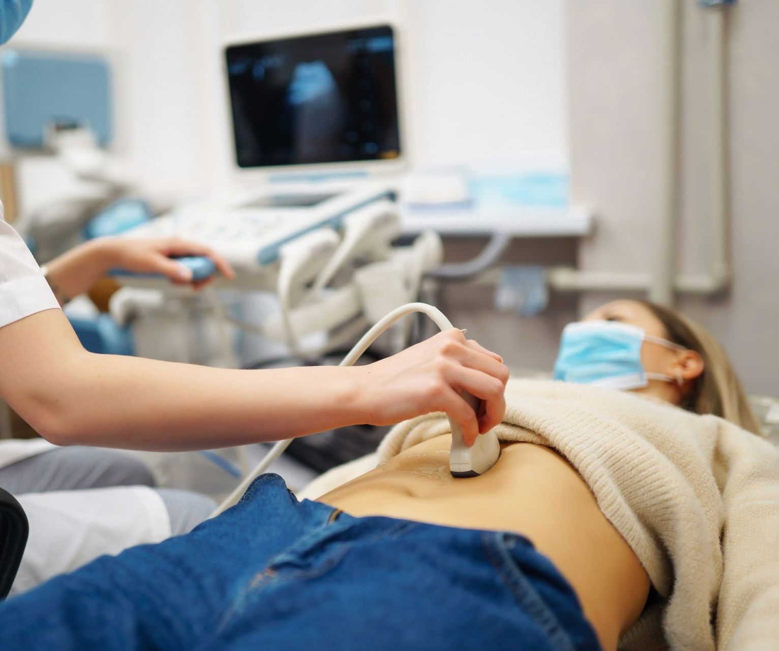 Un manipulateur effectue une échographie de l'abdomen d'une patiente