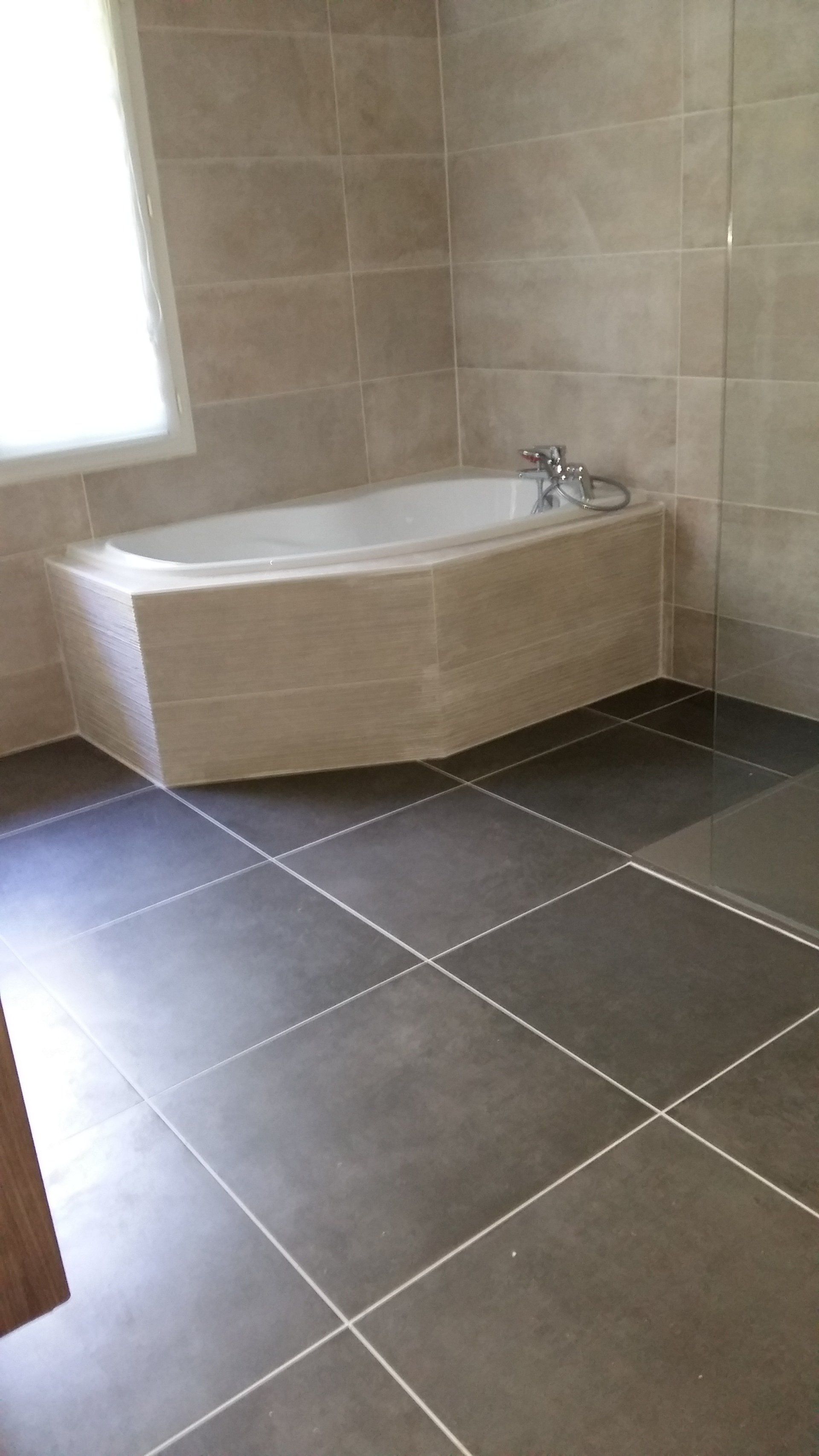 Baignoire d'angle posée sur du carrelage gris
