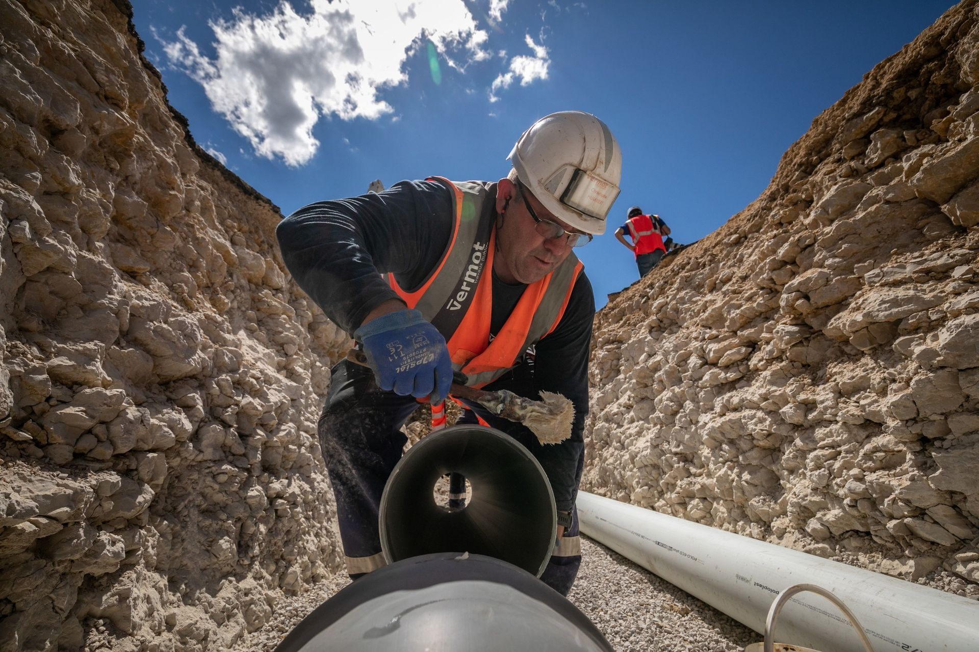 Ouvrier installant un tuyau d'une tranchée