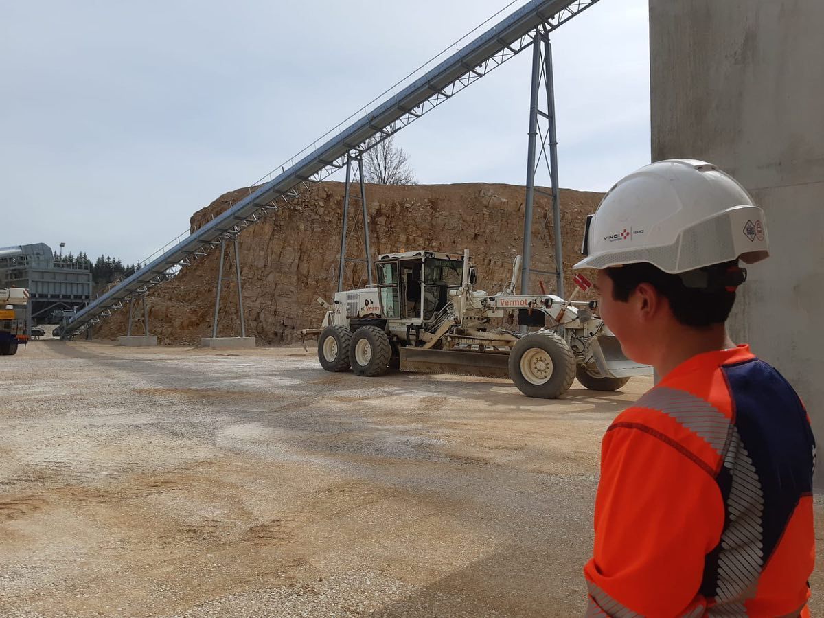 Apprenti en tenue de chantier regardant un engin Vermot