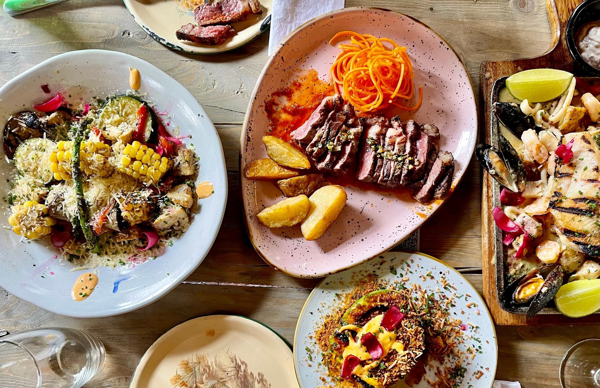 Una mesa cubierta con platos de comida y copas de vino.