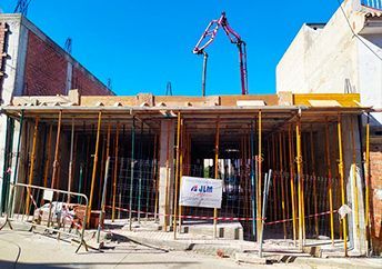Una obra en construcción con andamios y una grúa al fondo.