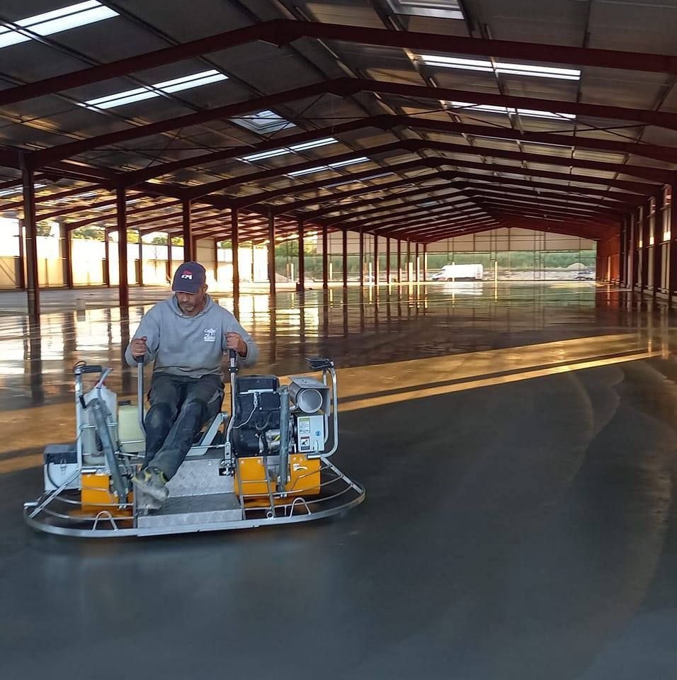 Un homme sur une machine qui pose du sol industriel