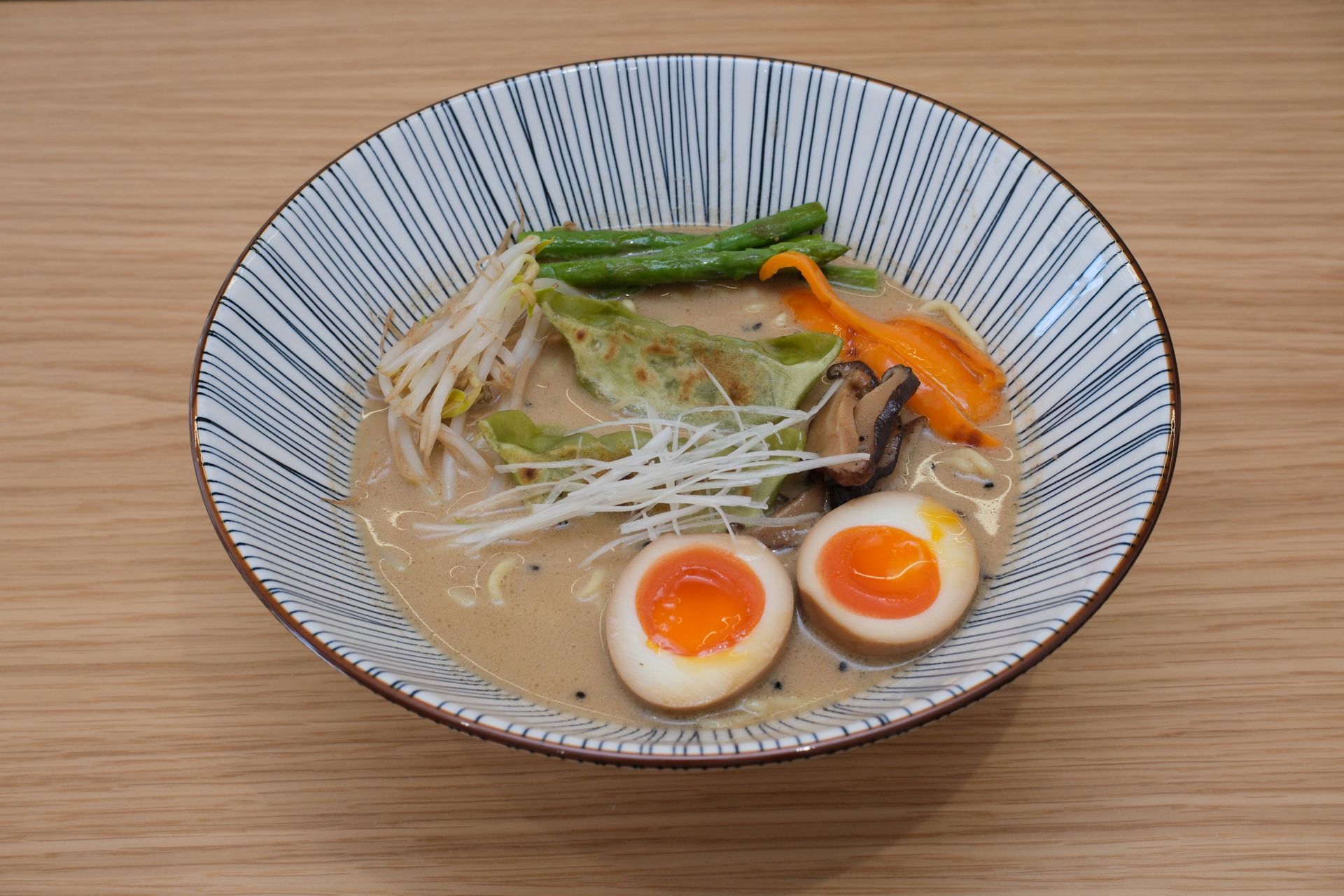 Tigela de ramen com macarrão, vegetais e ovos cozidos, em uma tigela com padrão azul e branco