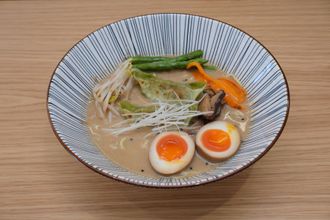 Tigela de ramen com macarrão, vegetais e ovos cozidos, em uma tigela com padrão azul e branco