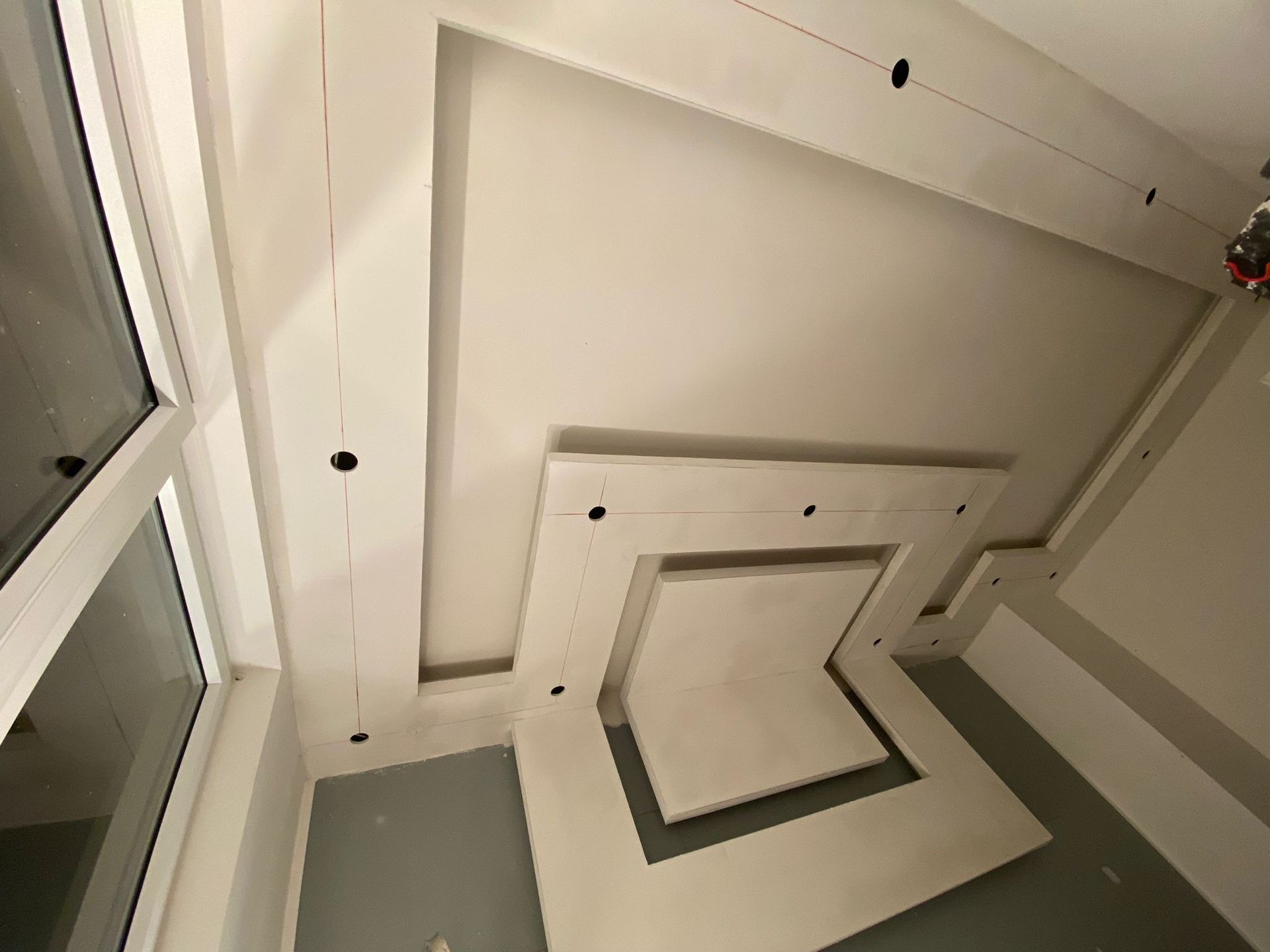 Ein Raum mit quadratischer Decke und einem Fenster.