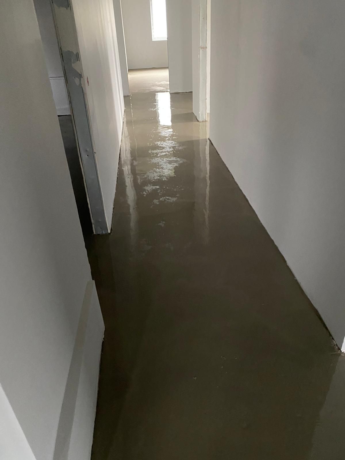 Ein Flur mit Betonboden und weißen Wänden.