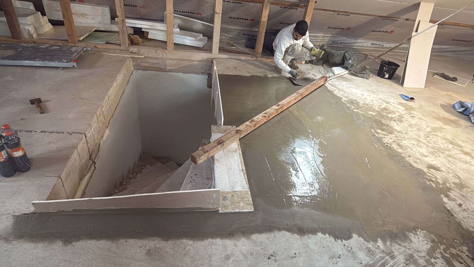 Ein Mann gießt Beton in ein Loch im Boden