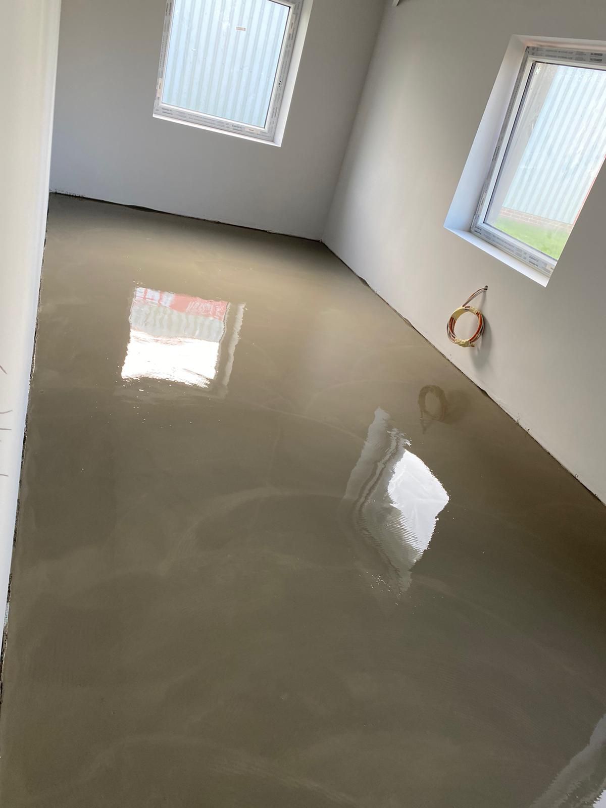 Ein Raum mit Betonboden und zwei Fenstern.