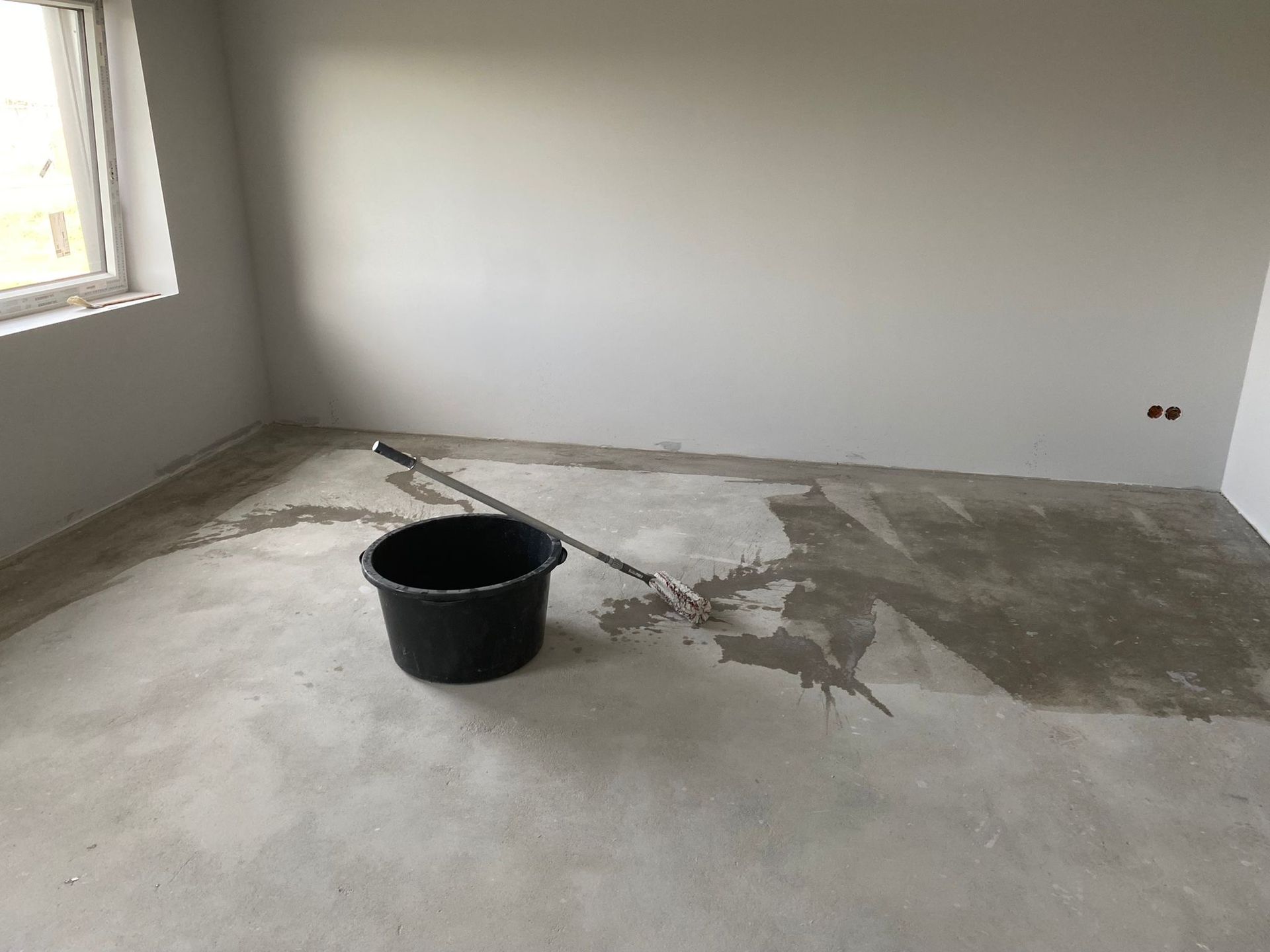 Ein Raum mit einem Eimer und einem Besen auf dem Boden.