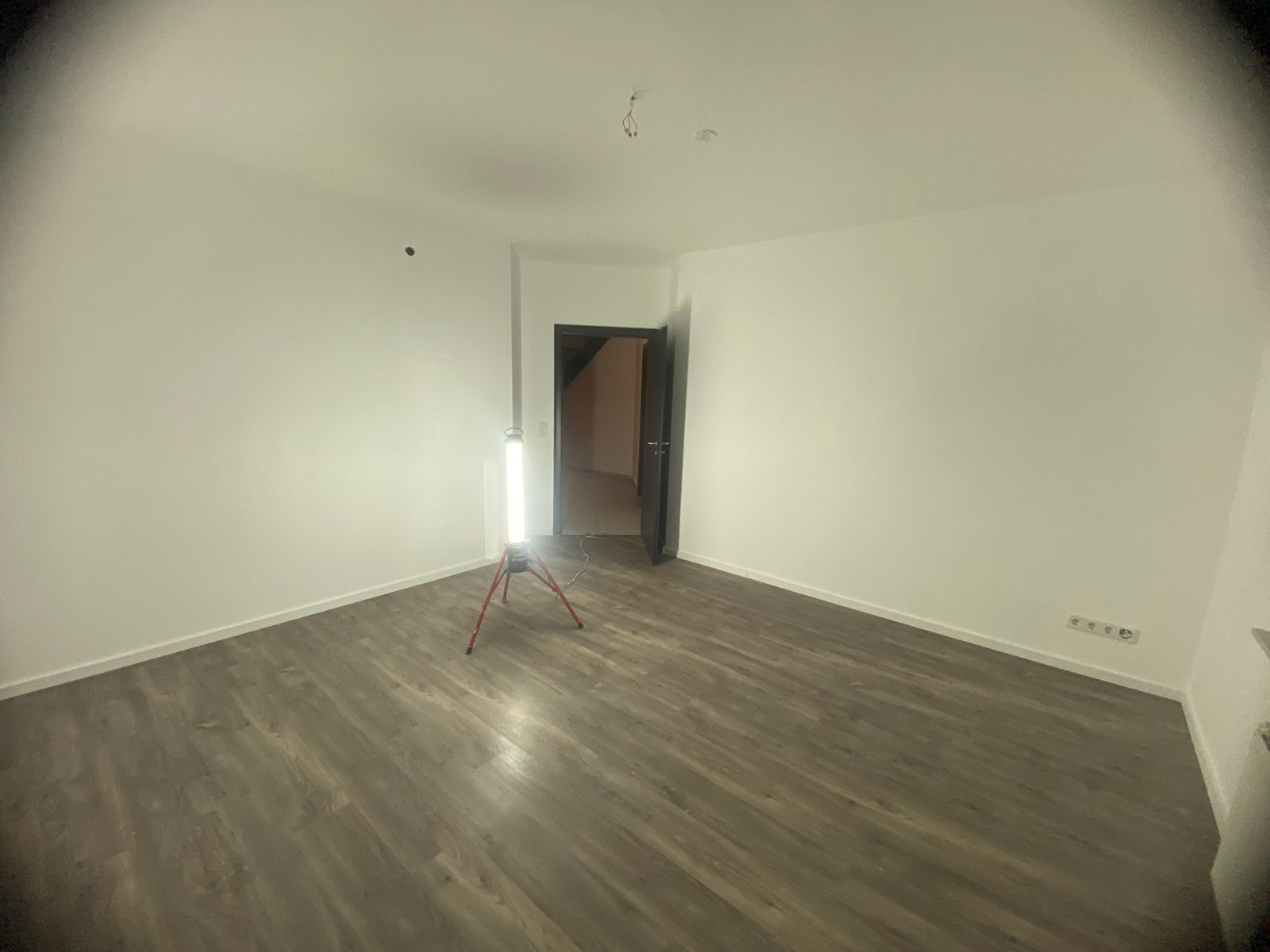 Ein leerer Raum mit einer Lampe auf einem Stativ in der Mitte.