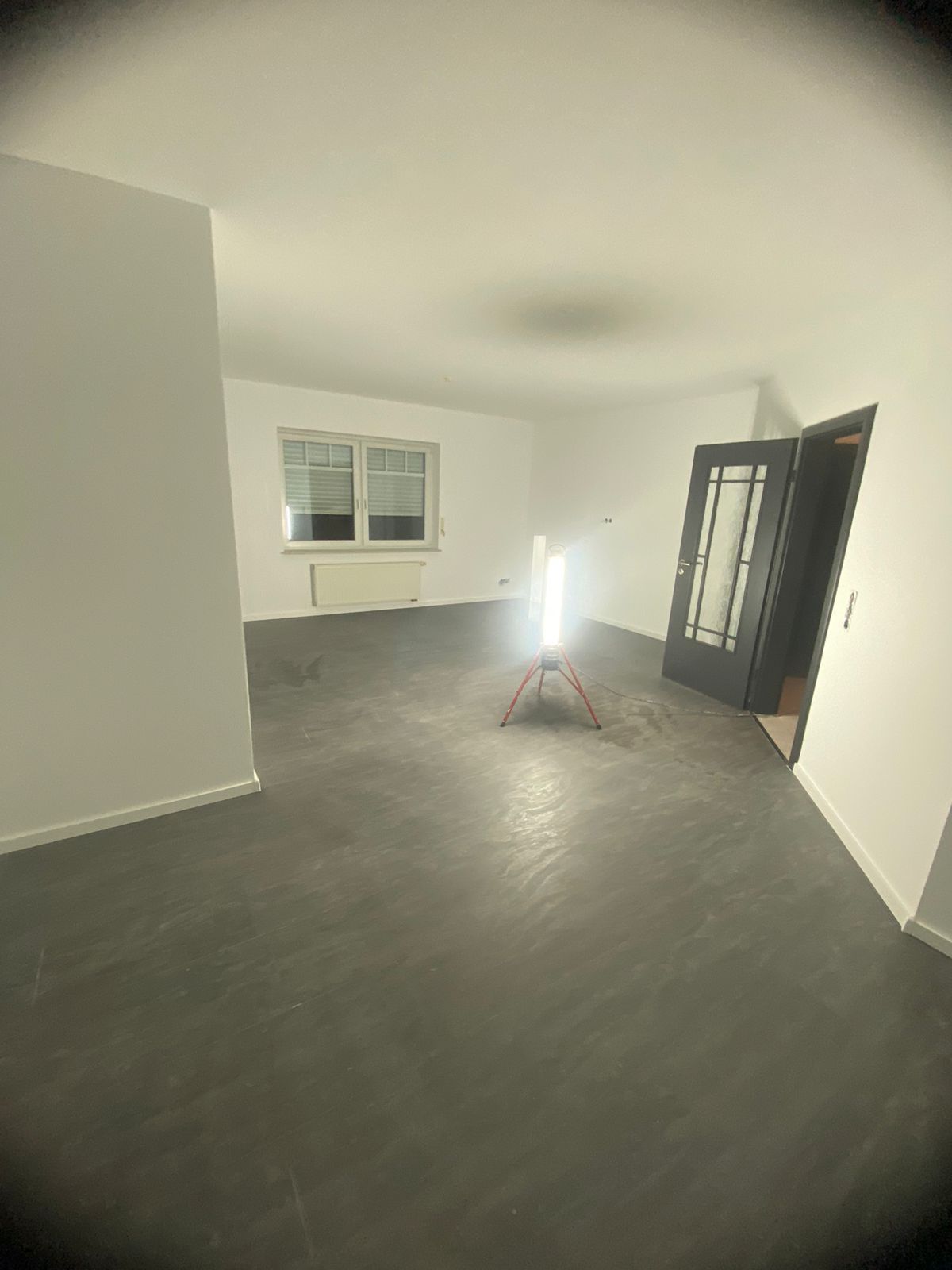 Ein leeres Wohnzimmer mit einer Lampe auf dem Boden.