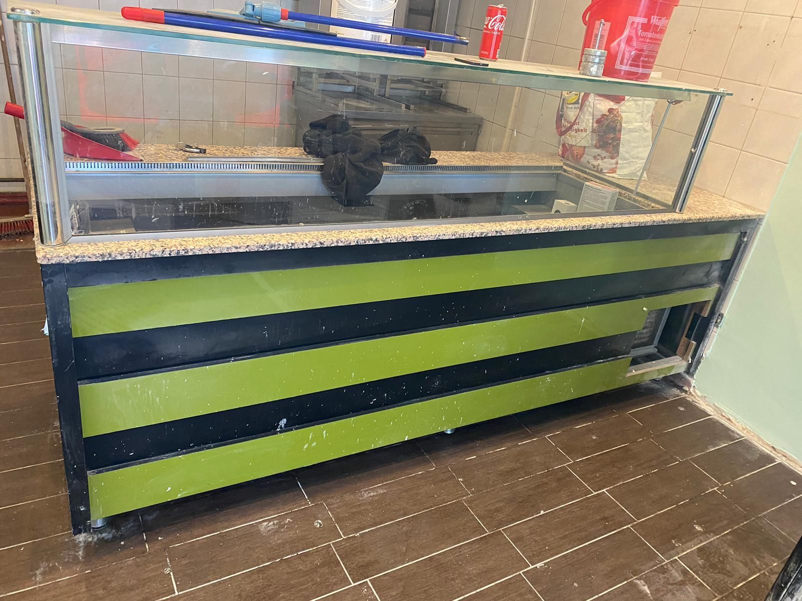 Eine grün-schwarze Theke mit einer Glasvitrine in einem Restaurant.
