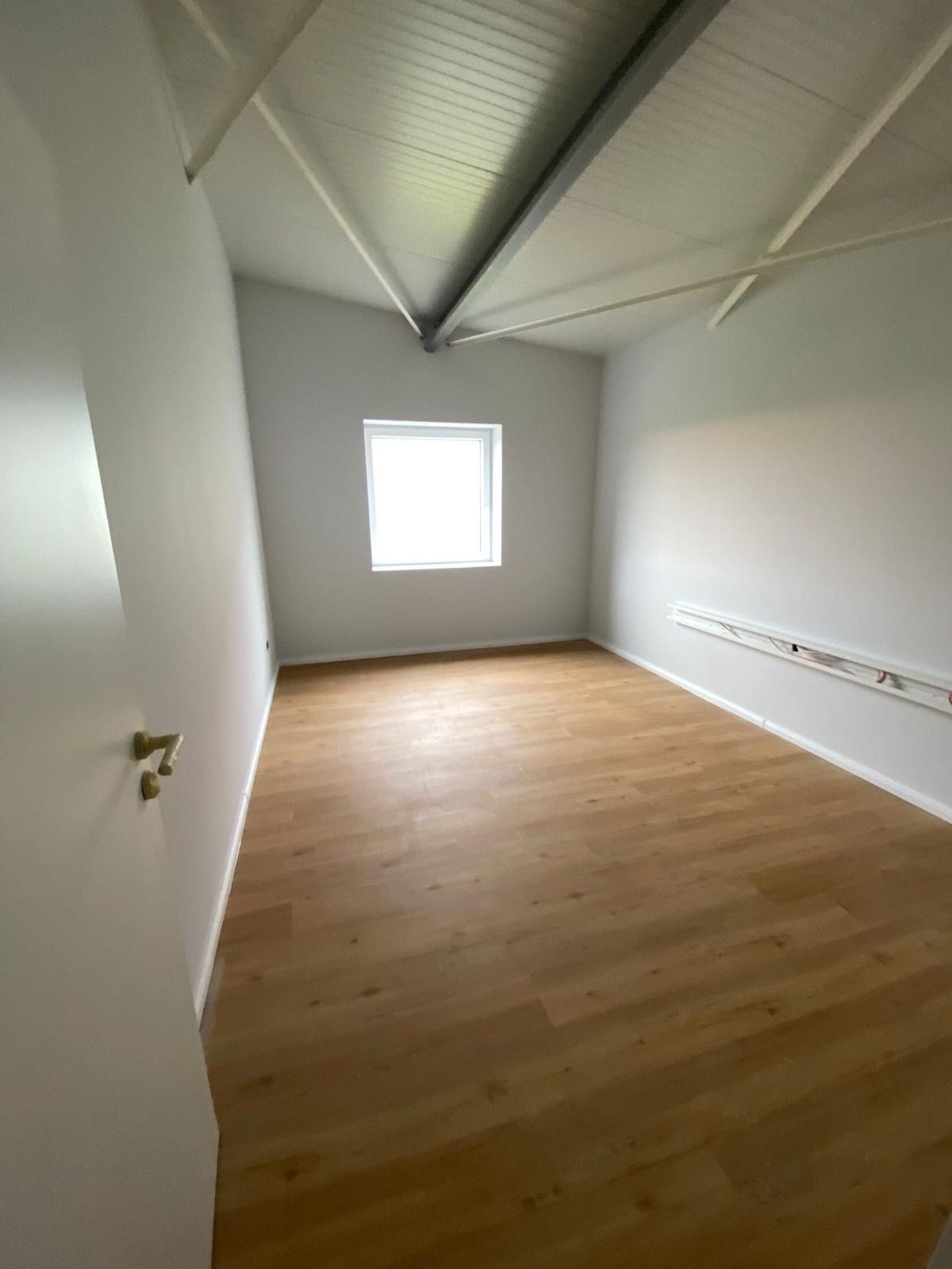 Ein leerer Raum mit Holzboden und einem Fenster.