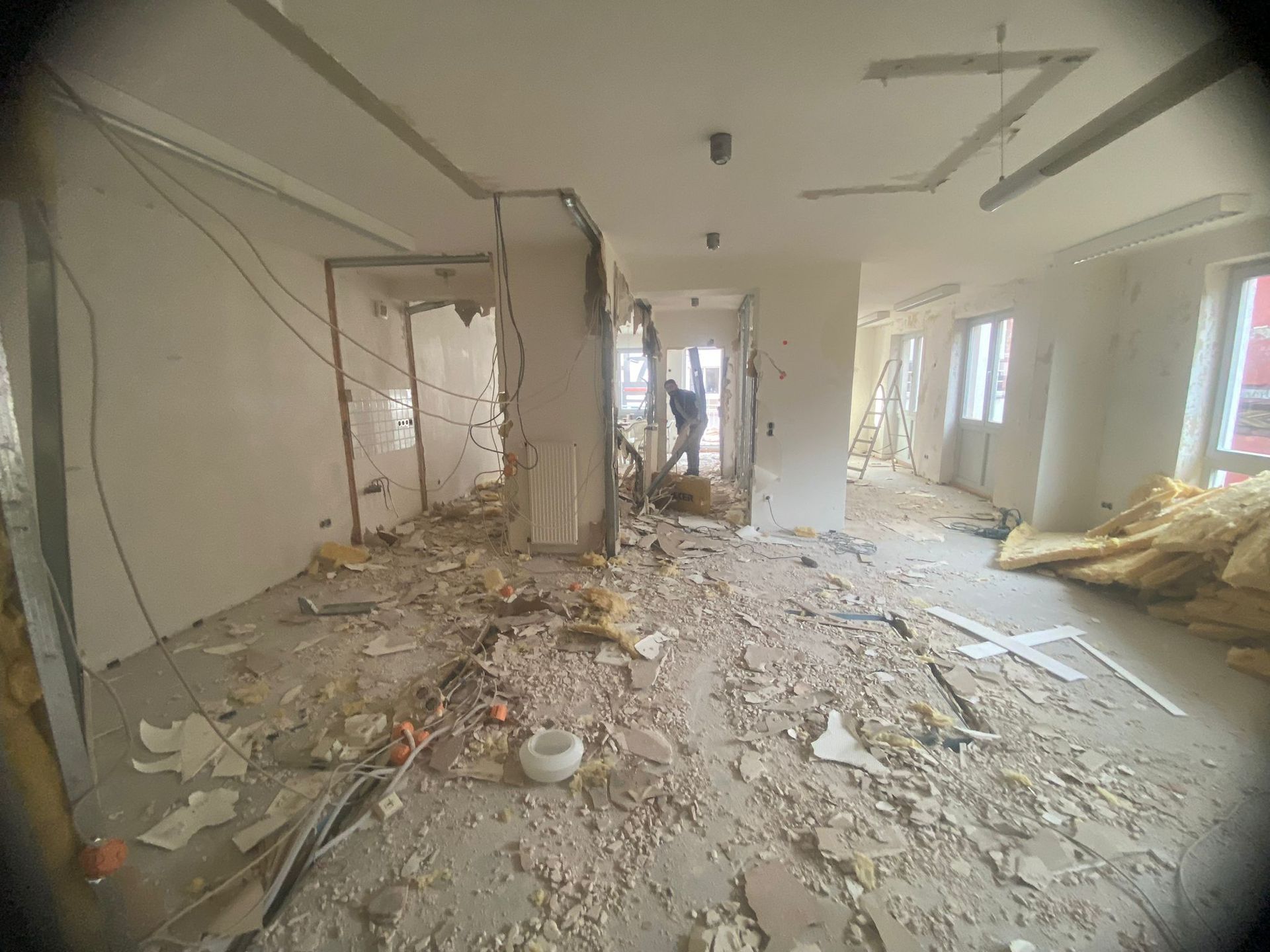 Ein Mann steht in einem Raum, auf dessen Boden viel Schutt liegt.