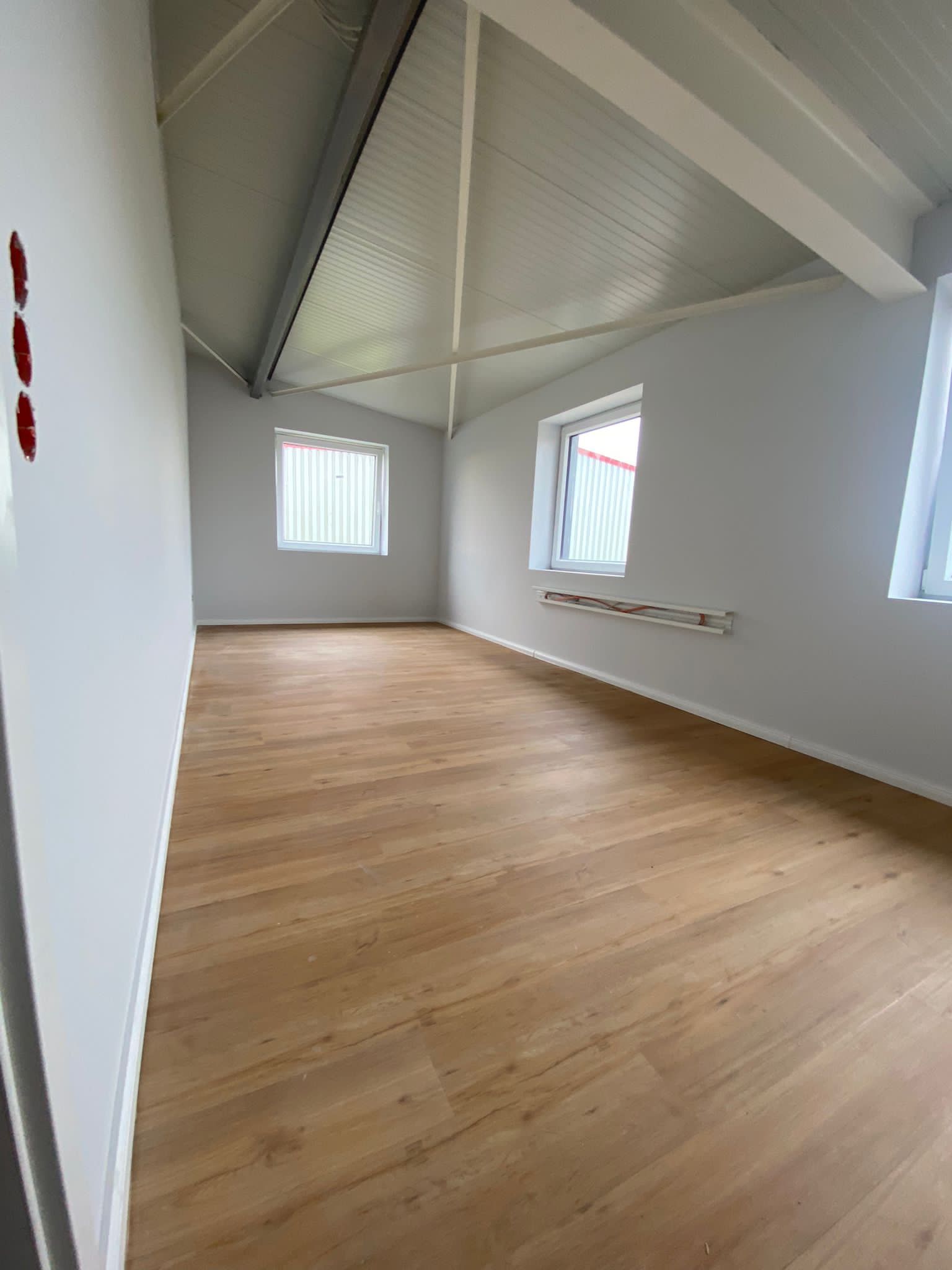Ein leerer Raum mit Holzboden und weißen Wänden.