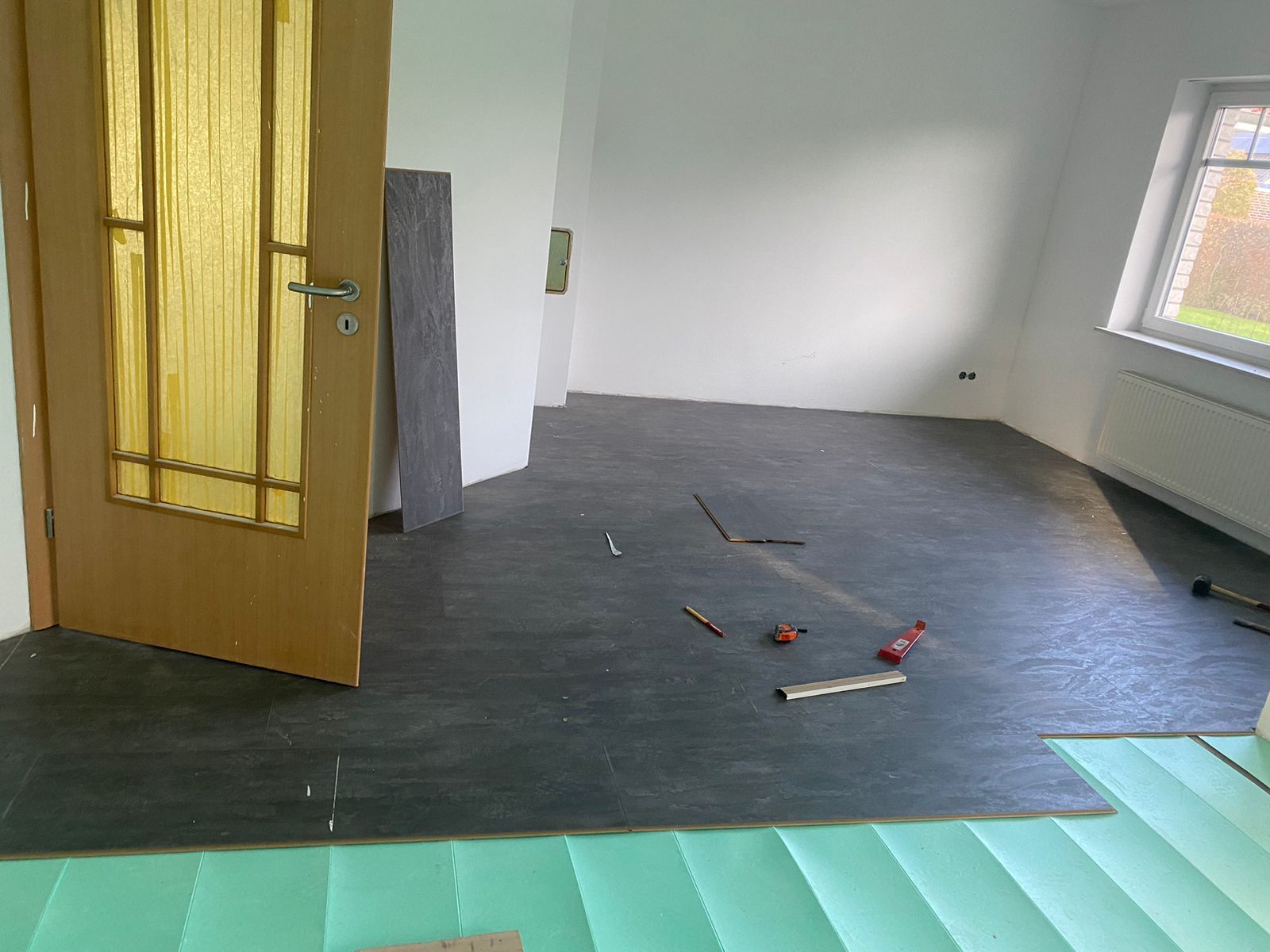 Ein Raum mit einer Holztür und einer grünen Matte auf dem Boden.