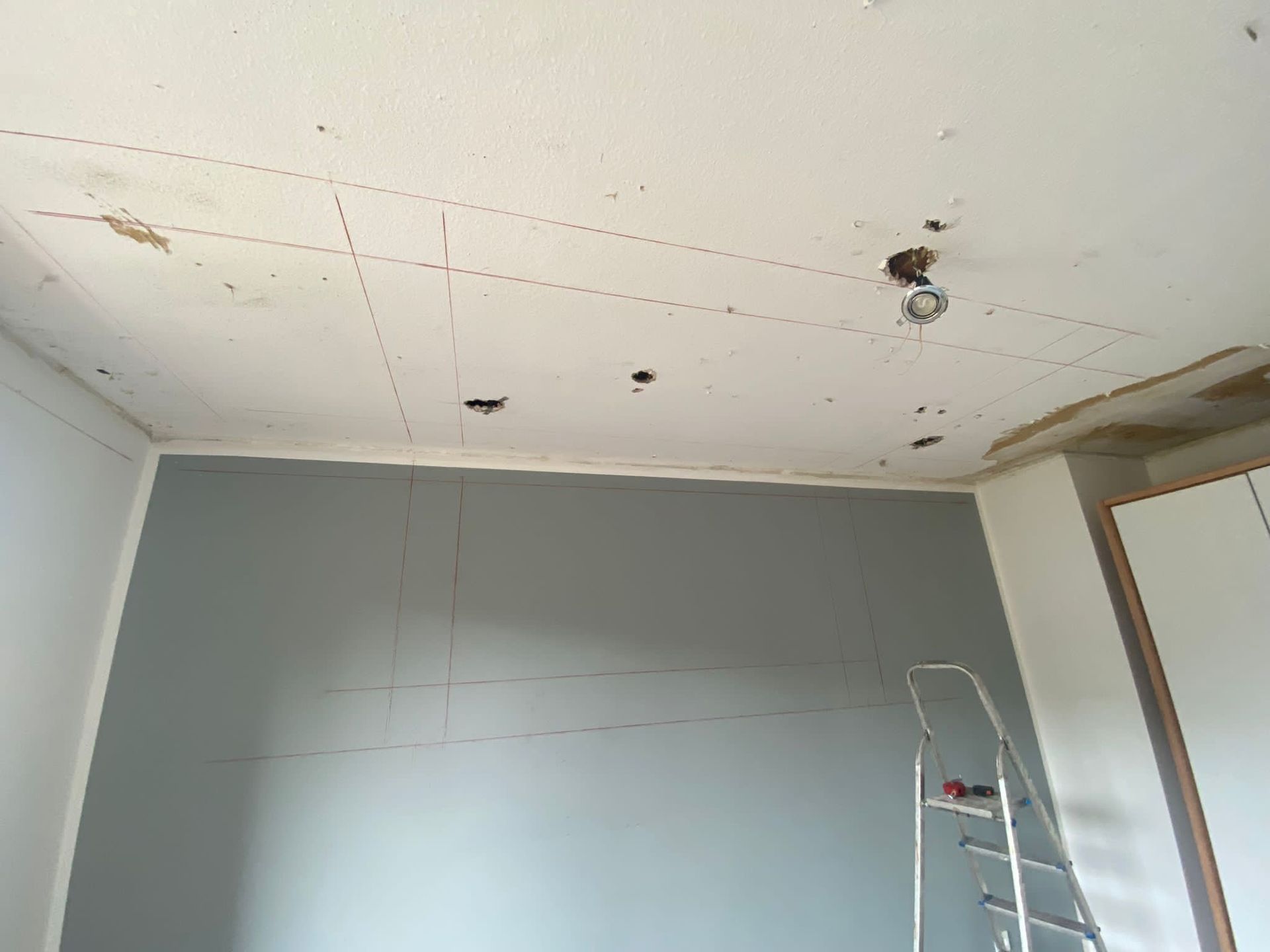 Ein Raum mit einer Leiter und einer Decke, die gerade renoviert wird.