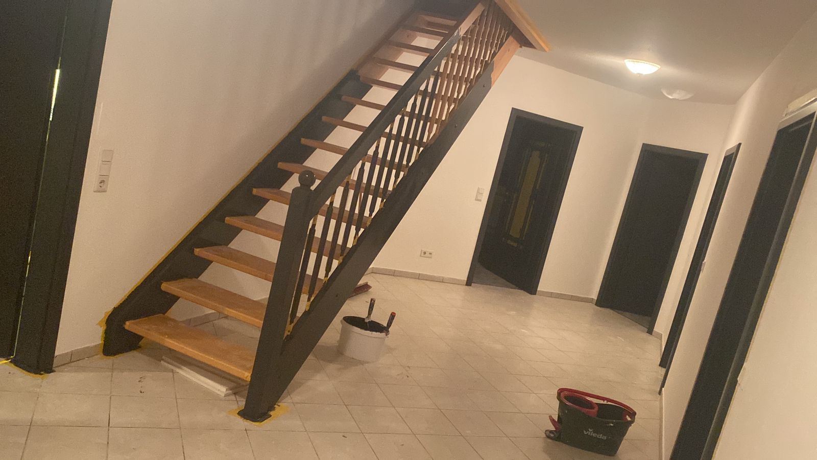 Eine Treppe mit Holzstufen und einem Metallgeländer in einem Flur.