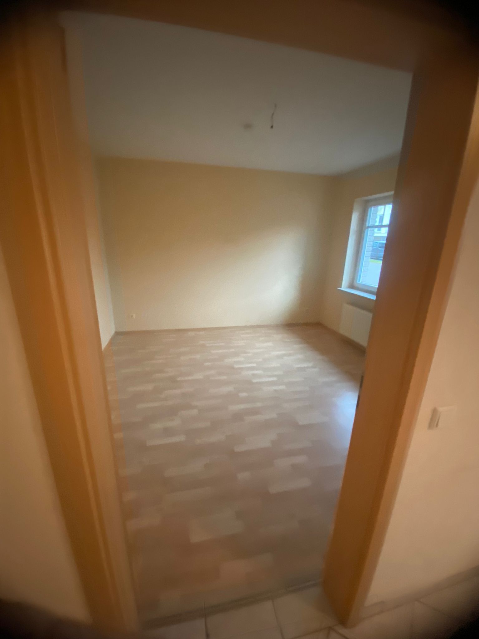 Ein leerer Raum mit Hartholzböden und einem Fenster.