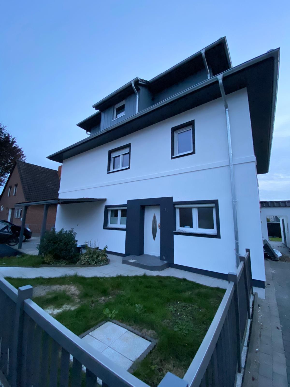 Ein großes weißes Haus mit einem Zaun davor