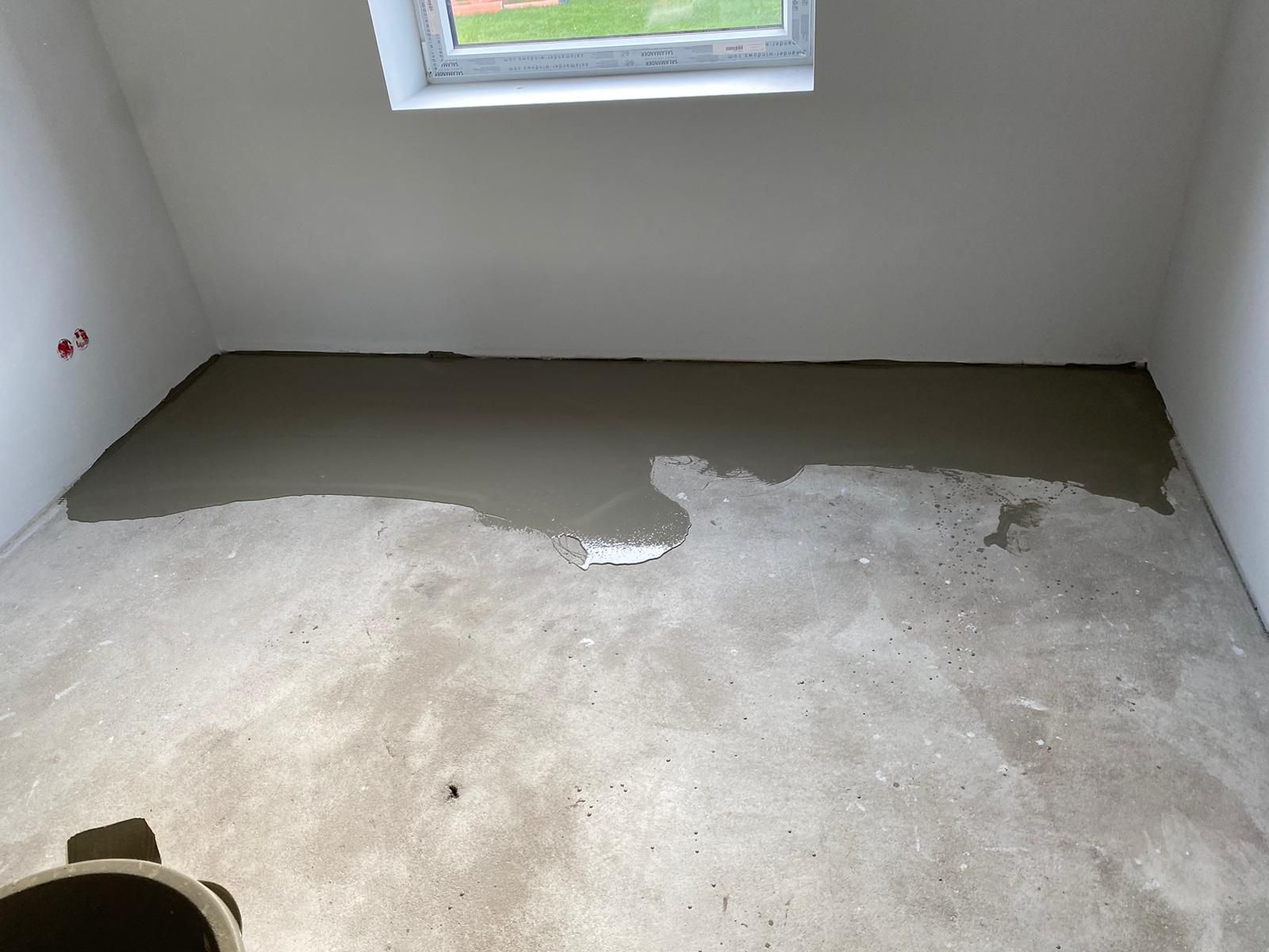 Ein Raum mit Betonboden und Fenster.