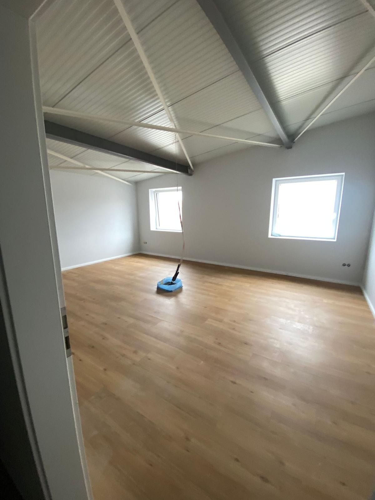 Ein leerer Raum mit Holzboden und weißen Wänden.