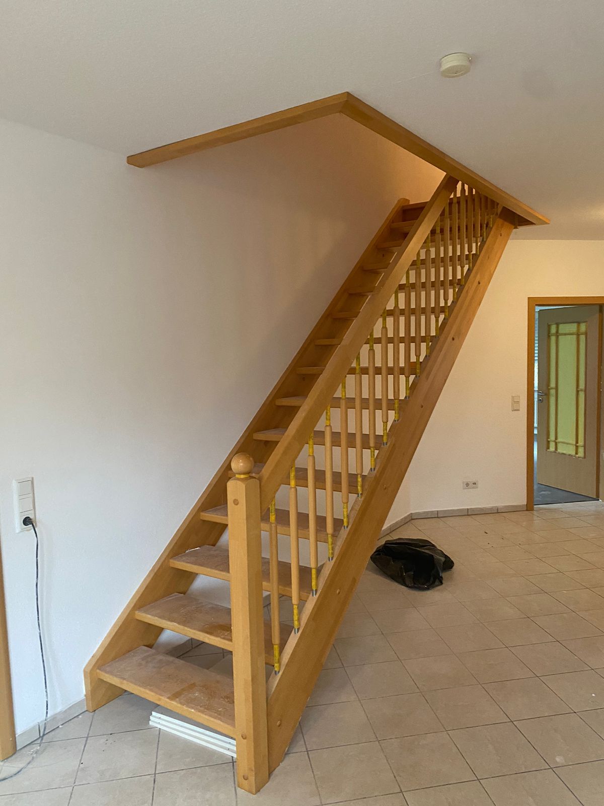 Eine Holztreppe in einem leeren Raum mit einem Hund, der auf dem Boden liegt.